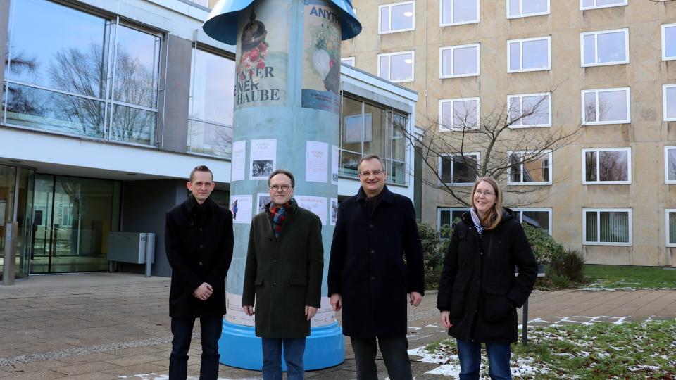 Die Teilnehmenden der Ausstellungseröffnung vor der Litfaßsäule.